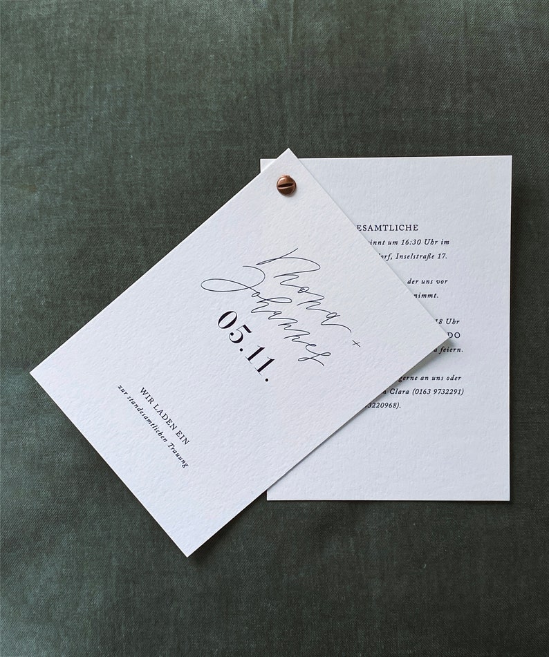 May include: A white wedding invitation with black text. The invitation reads "We are getting married on 05.11.  We invite you to our wedding ceremony at 4:30 PM at Inselstra&szlig;e 17.  We will celebrate afterwards at 8:00 PM.  Please RSVP to Clara at (0163) 9732291 or (0322) 20968."