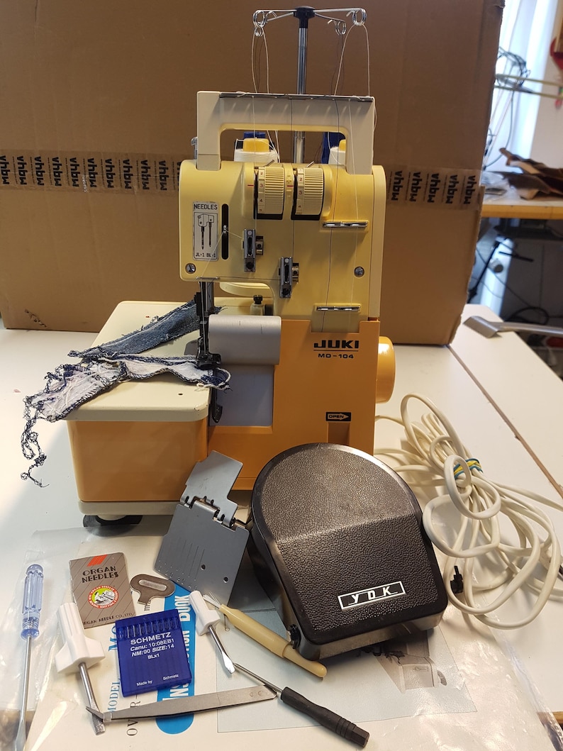 May include: A yellow JUKI MD-104 overlock sewing machine with a foot pedal and various sewing accessories, including needles, a screwdriver, and a key.