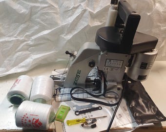 May include: A silver and black ZOTE brand bag sewing machine with a black foot pedal and two spools of white thread. The machine has a black belt and a label that reads "ZJ226-1A".