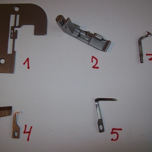 Może przedstawiać: Pięć srebrnych stop do maszyny do szycia, ponumerowanych od 1 do 5, na białym tle. Stopki mają różne kształty i rozmiary i są używane do różnych zadań szycia.