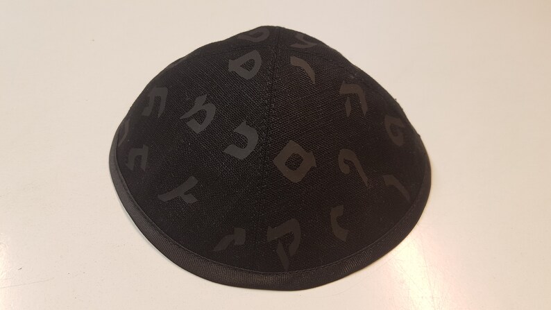 Pu&ograve; includere: Una kippah nera con un motivo ebraico.