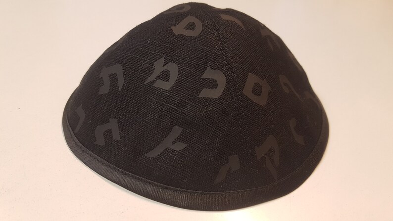 Pu&ograve; includere: Una kippah nera con un motivo di lettere ebraiche.