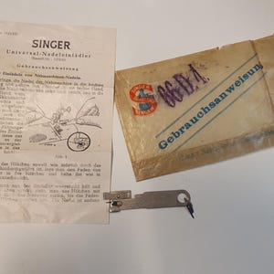 May include: Vintage Singer Universal Needle Threader set, including instructions and original packaging. The set includes a metal needle threader tool, a paper instruction sheet, and a paper envelope with the Singer logo.