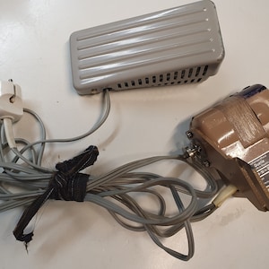 May include: A grey foot pedal with a cord and plug, and a brown electric motor with a cord and plug. The motor has a label that reads "Qualite N-1000 72 Watt 12-15 Volt".