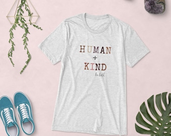 Puede incluir: Una camiseta gris jaspeada con el texto "HUMAN + KIND be both" impreso en marrón, rosa y beige. El texto está estilizado con diferentes tonos de marrón, rosa y beige para representar diferentes tonos de piel.