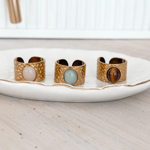 May include: A set of three ceramic mugs with a speckled, matte finish. Each mug is a different colour: light blue, cream, and grey. The mugs have a simple, modern design, ideal for coffee or tea.