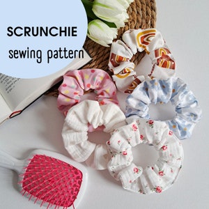 May include: Five fabric scrunchies in different patterns. The scrunchies are made of soft, colorful fabric and are perfect for adding a touch of style to any outfit.  The scrunchies are arranged on a white surface with a book and a hairbrush.