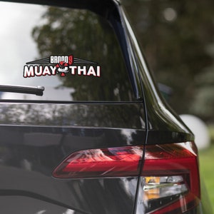May include: A black car with a red and white sticker that says "BROOD 9 MUAY THAI" on the back window.