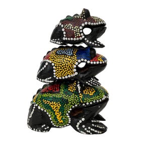 May include: Three stacked, hand-painted wooden frog sculptures. Each frog is black with colorful dot patterns in red, yellow, blue, and green. The frogs have open mouths and are stacked on top of each other.