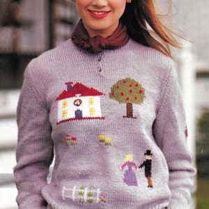 May include: A lilac-coloured sweater featuring a knitted design of a house, a tree with red dots, and a couple. The sweater has a crew neck, a ribbed texture, and a buttoned neckline. The design is reminiscent of a countryside scene.