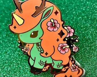 May include: A green and orange enamel pin featuring a cartoon unicorn with antlers, a horn, and flowers. The unicorn is standing on a cloud.