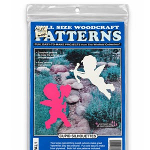 May include: A clear plastic package containing full size woodcraft patterns for Cupid silhouettes. The blue header reads Full Size Woodcraft Patterns. The package includes two 34 inch long patterns for plywood cutouts, featuring a pink and a white Cupid.