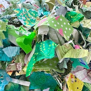 May include: A pile of fabric scraps in various shades of green, teal, and white. The scraps are cut into irregular shapes and feature floral, polka dot, and abstract patterns. The image is a close-up, showing the texture and detail of the fabric.