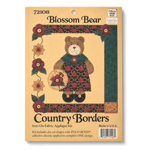 May include: A Blossom Bear Country Borders iron-on fabric appliqué kit in a tan package. The graphic shows a brown bear wearing a dark green collar and a black dress with red floral patterns, holding a circular floral accent piece.