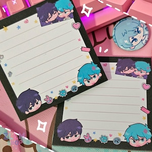 May include: Two black and white notepads with a lined white interior. The notepads have a black border and are decorated with colorful cartoon characters and stars.