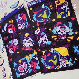 May include: Sticker sheets with cartoon character designs. The stickers, set against a black backdrop, showcase vibrant illustrations of characters adorned with heart-shaped glasses, crowns, and other embellishments. Text includes "ZLLM SHOP", "STOLITZ", "FIZZMODEUS", and "OZZIE".