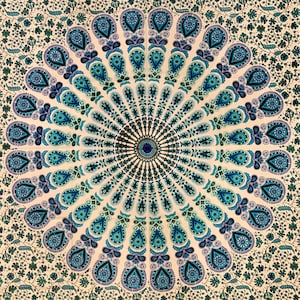 Puede incluir: Un tapiz blanco con un diseño de mandala azul y verde. El mandala presenta un patrón circular con detalles intrincados y un círculo central.
