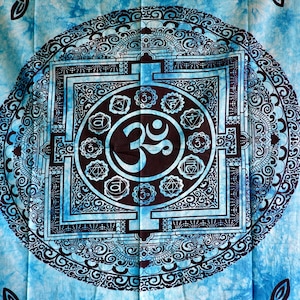 May include: A blue tapestry with a mandala design featuring a large Om symbol in the centre. The mandala is surrounded by a square with smaller symbols and a circle of intricate patterns.