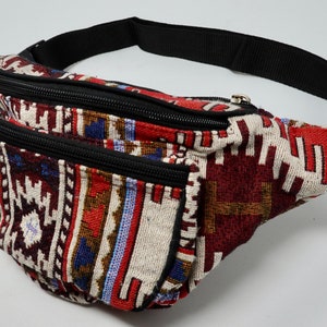 May include: A multi-coloured fanny pack with a black adjustable strap and two zippered compartments. The fabric features a geometric pattern in shades of red, blue, white, and brown.