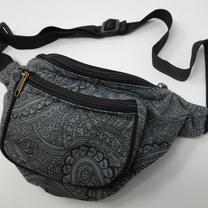 Op de afbeelding: Een grijze heuptas met een zwart paisley-patroon en twee ritsvakken. De heuptas heeft een zwarte verstelbare band.