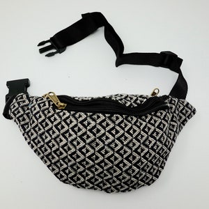May include: Black and white geometric patterned fanny pack with a black adjustable strap and a gold zipper.