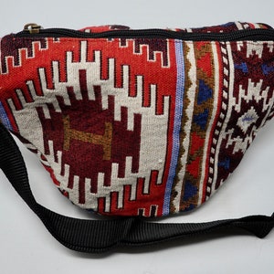 May include: A red, white and blue patterned fanny pack with a black adjustable strap and buckle.