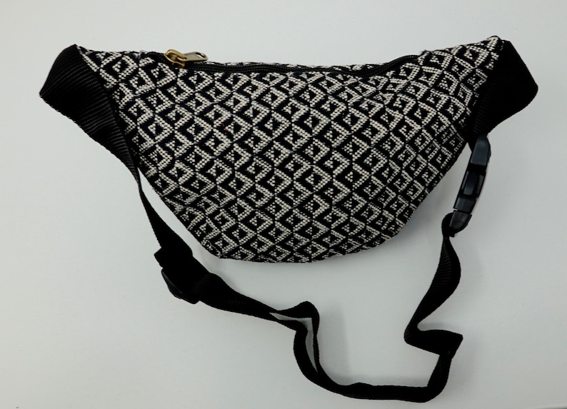 May include: Black and white patterned bum bag with a black adjustable strap. The bum bag has a zipper closure.