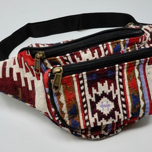 May include: A red, white and blue patterned bum bag with two zipped compartments and a black adjustable strap.