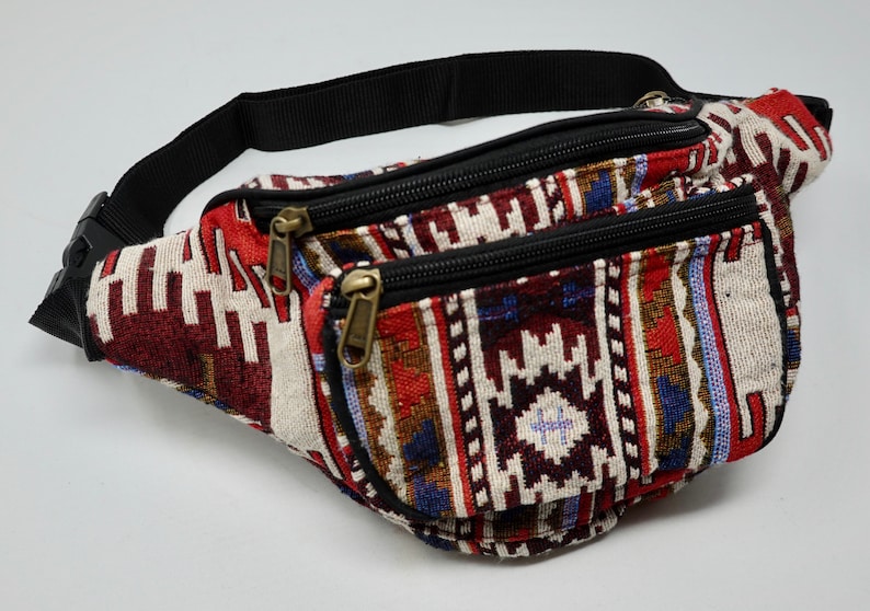 May include: A red, white and blue patterned bum bag with two zipped compartments and a black adjustable strap.