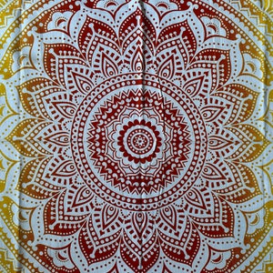 May include: A white tapestry with a red and yellow mandala design. The mandala has intricate details and a circular pattern.