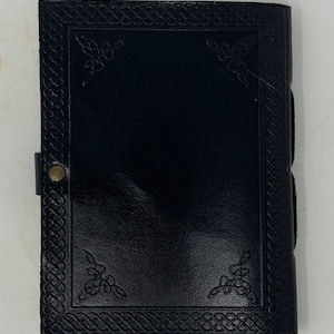 May include: Black leather journal with a Celtic knot border and decorative corner designs.