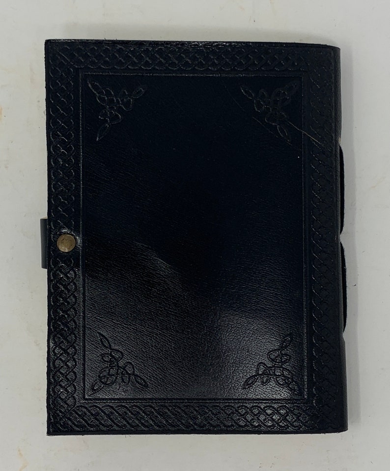 May include: Black leather journal with a Celtic knot border and decorative corner designs.