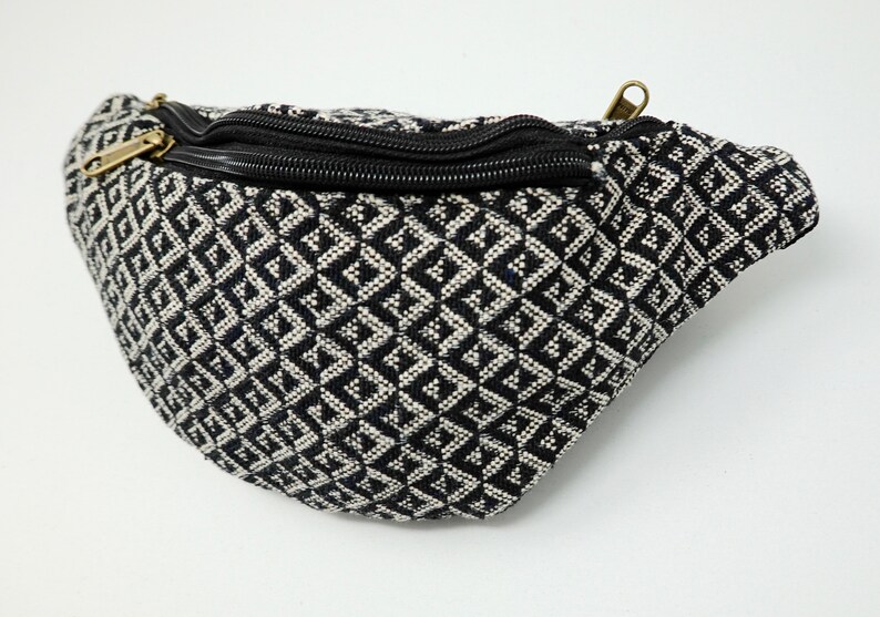 May include: Black and white geometric patterned fanny pack with a black zipper and a gold zipper pull.