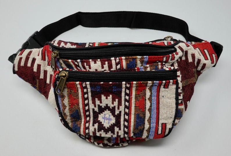 May include: A red, white and blue patterned fanny pack with two zipped compartments and a black adjustable strap.