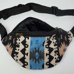 Pu&ograve; includere: Una marsupio nera con un motivo geometrico blu, bianco e marrone. La marsupio ha una chiusura a zip e una tracolla nera regolabile.