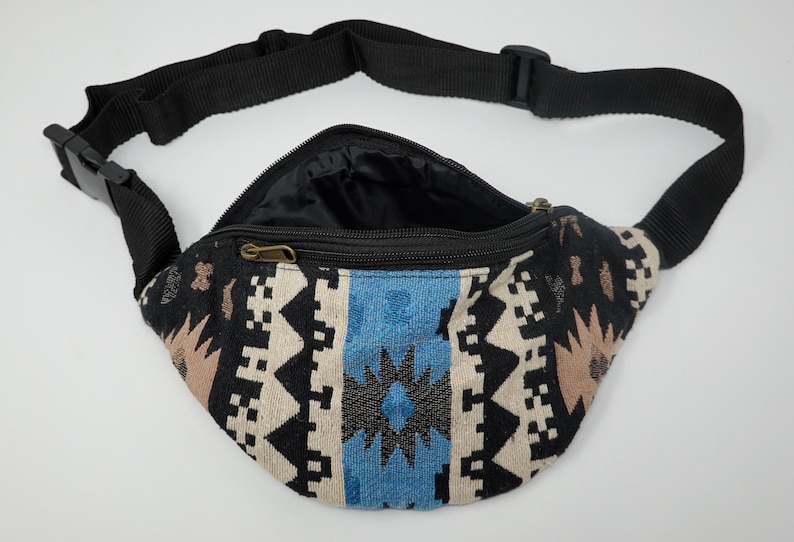 Pu&ograve; includere: Una marsupio nera con un motivo geometrico blu, bianco e marrone. La marsupio ha una chiusura a zip e una tracolla nera regolabile.