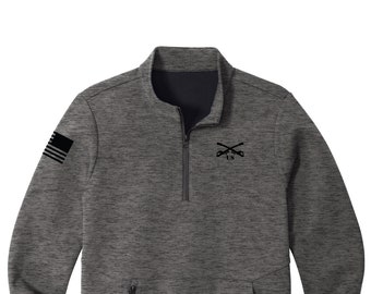 Puede incluir: Una sudadera de color gris y negro con cremallera de un cuarto de vuelta y un logotipo bordado en negro en el pecho. El logotipo presenta rifles cruzados y las letras "US". La manga izquierda tiene un diseño de bandera estadounidense en blanco y negro.