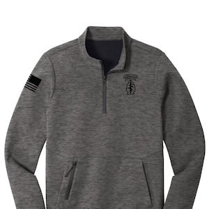 May include: A gray and black long-sleeve pullover with a zipper. The shirt has a pocket on the left side and a black patch on the right side with the text "SPECIAL FORCES AIRBORNE".
