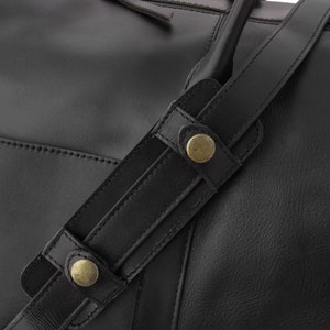 May include: Black leather duffel bag with a top zipper closure and two adjustable straps with brass buckles.