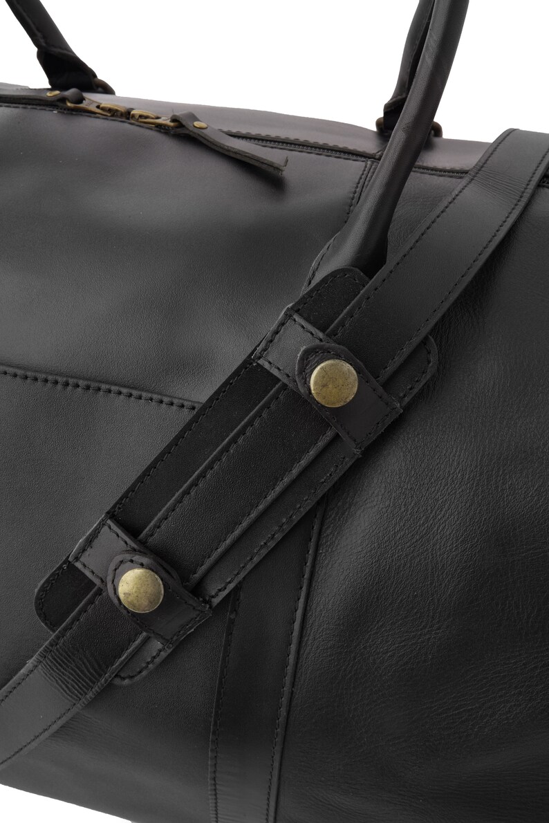 May include: Black leather duffel bag with a top zipper closure and two adjustable straps with brass buckles.