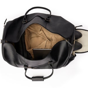 May include: A black leather duffel bag with a brown lining. The bag is open and has a laptop, a jacket, and shoes inside.