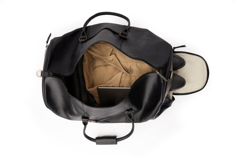 May include: A black leather duffel bag with a brown lining. The bag is open and has a laptop, a jacket, and shoes inside.