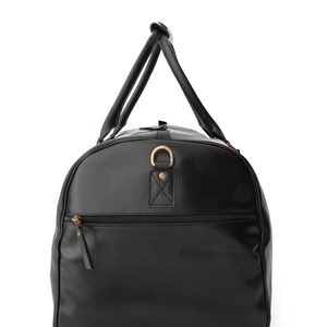 May include: A black leather duffel bag with a top handle and a zippered pocket on the front.