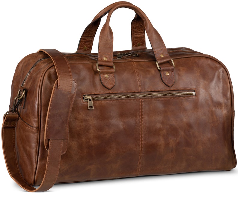 May include: A brown leather duffel bag with a top handle and a shoulder strap. The bag has a zippered pocket on the front and brass hardware.
