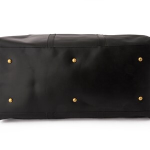 May include: Black leather duffel bag with gold metal accents. The bag has a zipper closure and a top handle.