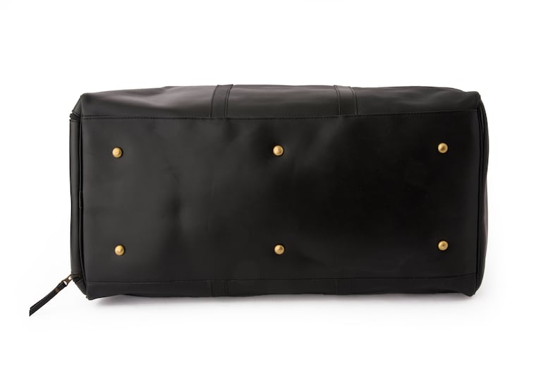 May include: Black leather duffel bag with gold metal accents. The bag has a zipper closure and a top handle.