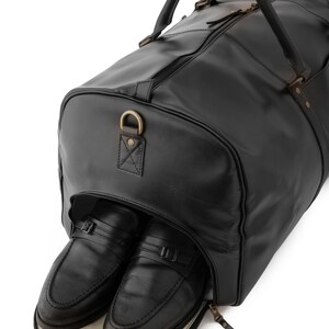 May include: A black leather travel bag with a zippered opening, revealing two black leather shoes inside.