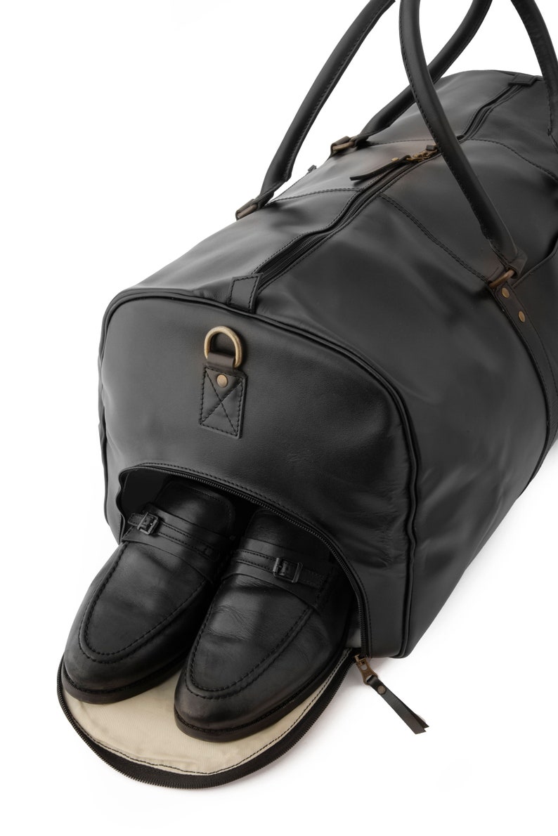 May include: A black leather travel bag with a zippered opening, revealing two black leather shoes inside.