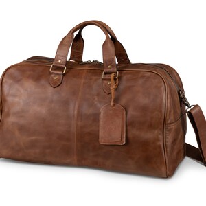 May include: A brown leather duffel bag with a top handle and a shoulder strap. The bag has a brass zipper and a brass tag.