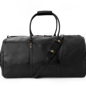 May include: A black leather duffel bag with a top handle and a shoulder strap. The bag has gold-colored hardware and a zipper closure.